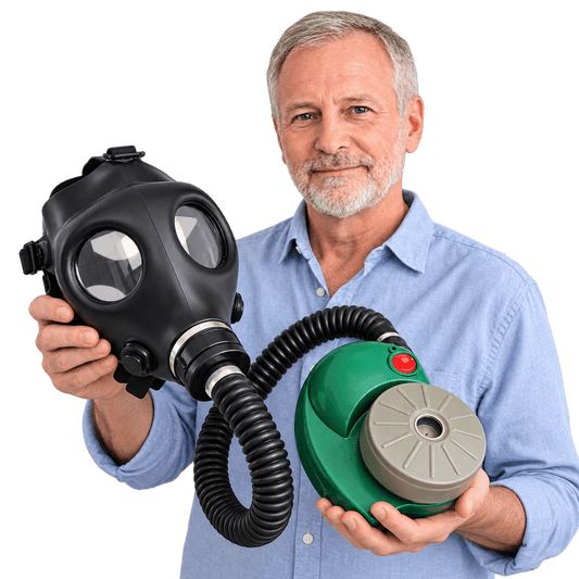 A man in a light blue button-down shirt holds a black gas mask with a flexible hose connected to a green PAPR Device With A filter against a solid white background